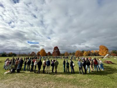 A large group of people, gathered in a circle, in an open field