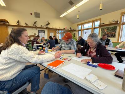 People sit around tables, talking and drawing
