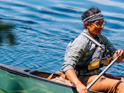 Damon Galipeau, a cohort 2 grantee, pictured on the water paddling in a green canoe and life jacket.