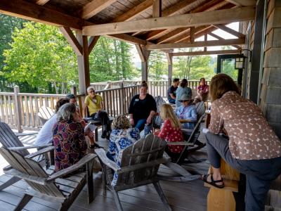 12 people sitting on a porch in the summer clearly engaged in dialogue