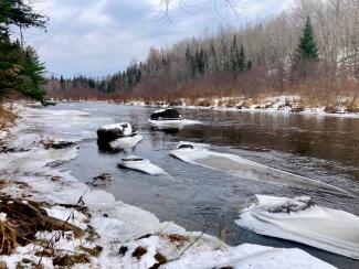 An icy river winds through a winter forest