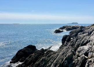 Rocky island cliffs, and the ocean, on a sunny day. This island is one of the Tributary Land Returns.