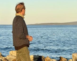 A man looks out over the ocean, at dawn